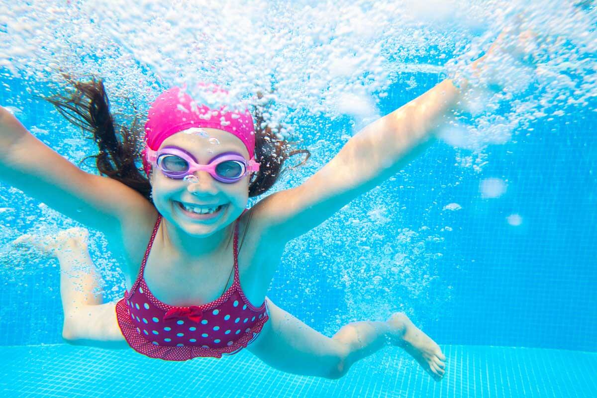 girl in a pink hat smiling underwater