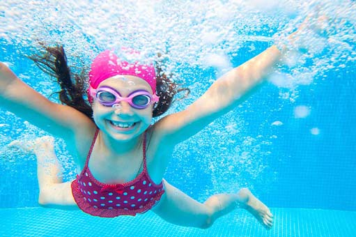 girl in a pink hat diving underwater