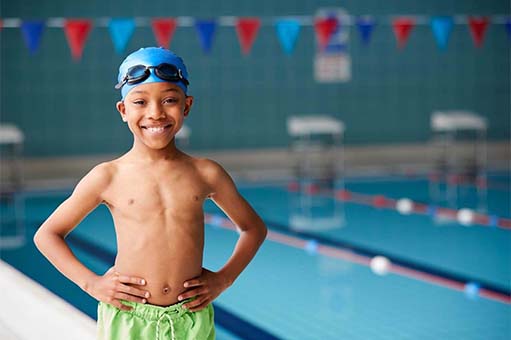 young boy standing at the edge of a swimming pool